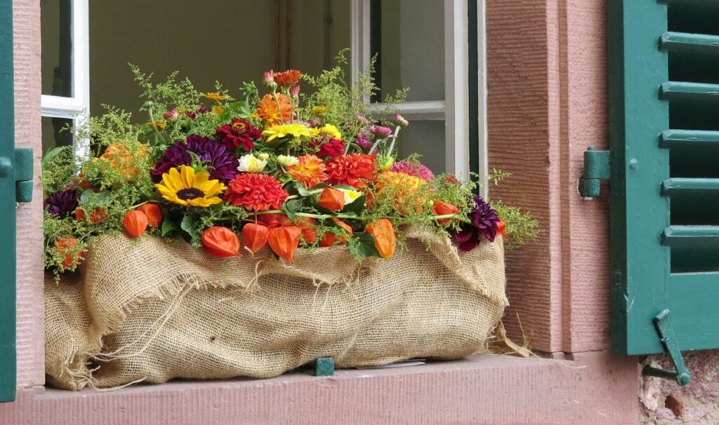 Herbst Dekor mit bunten Blumen und Zeigen, natürlichen Stoffen wie Leinen.